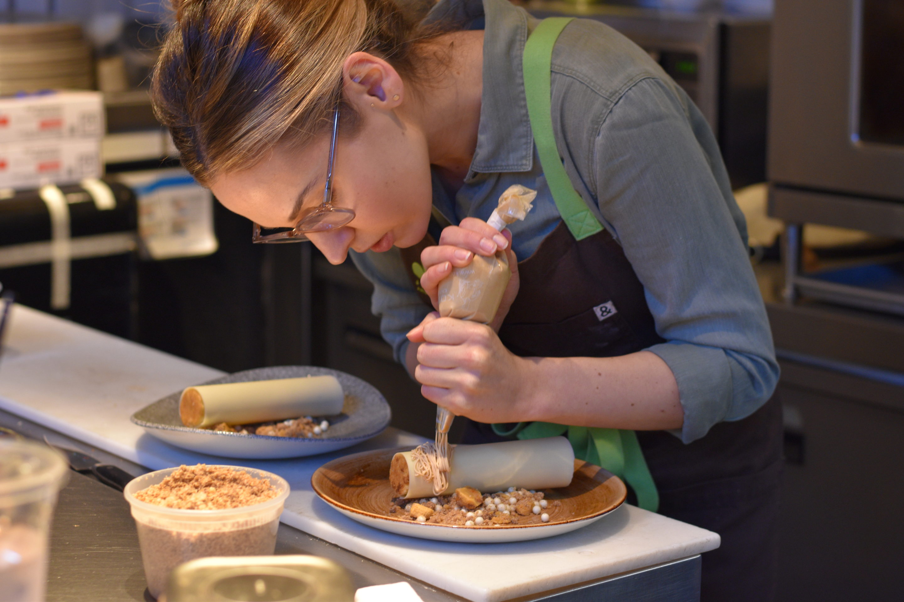 woman piping icing onto dessert