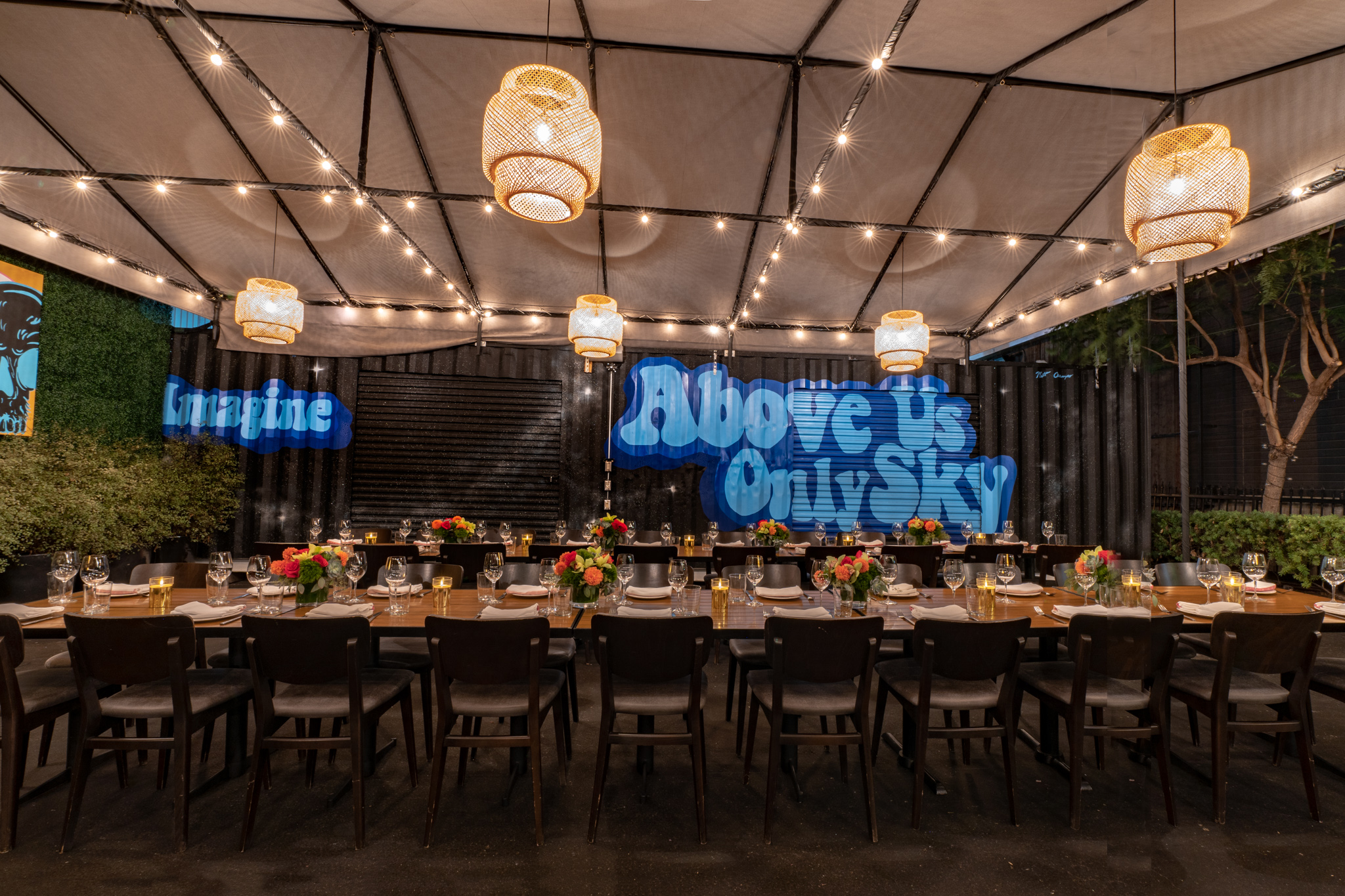 Shot of outdoor area under a tent with two large tables and painting behind