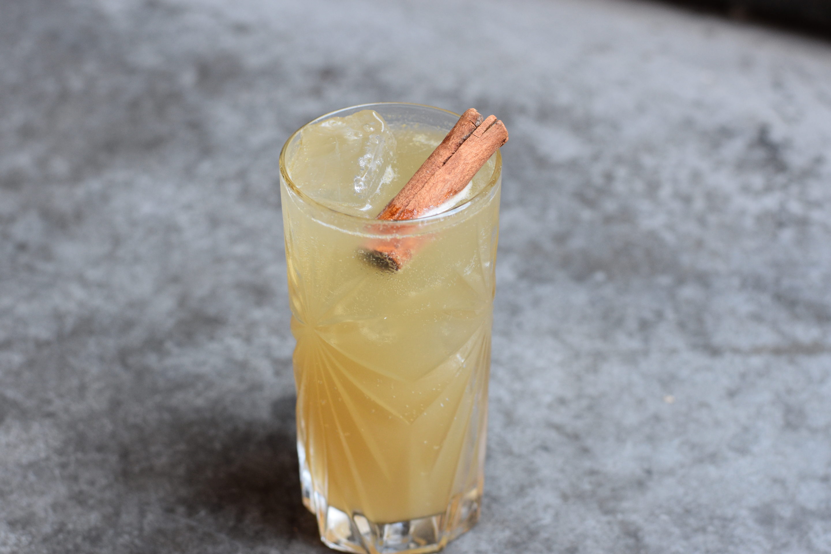 Brown cocktail with a cinnamon stick floating on top