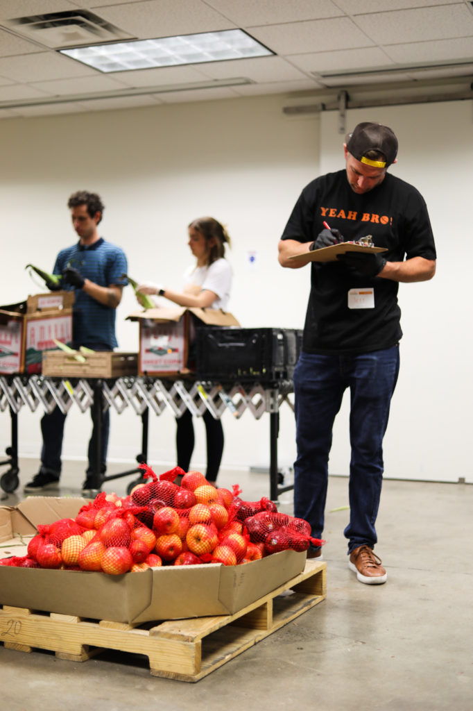 man with clipboard in front of barrel of apples