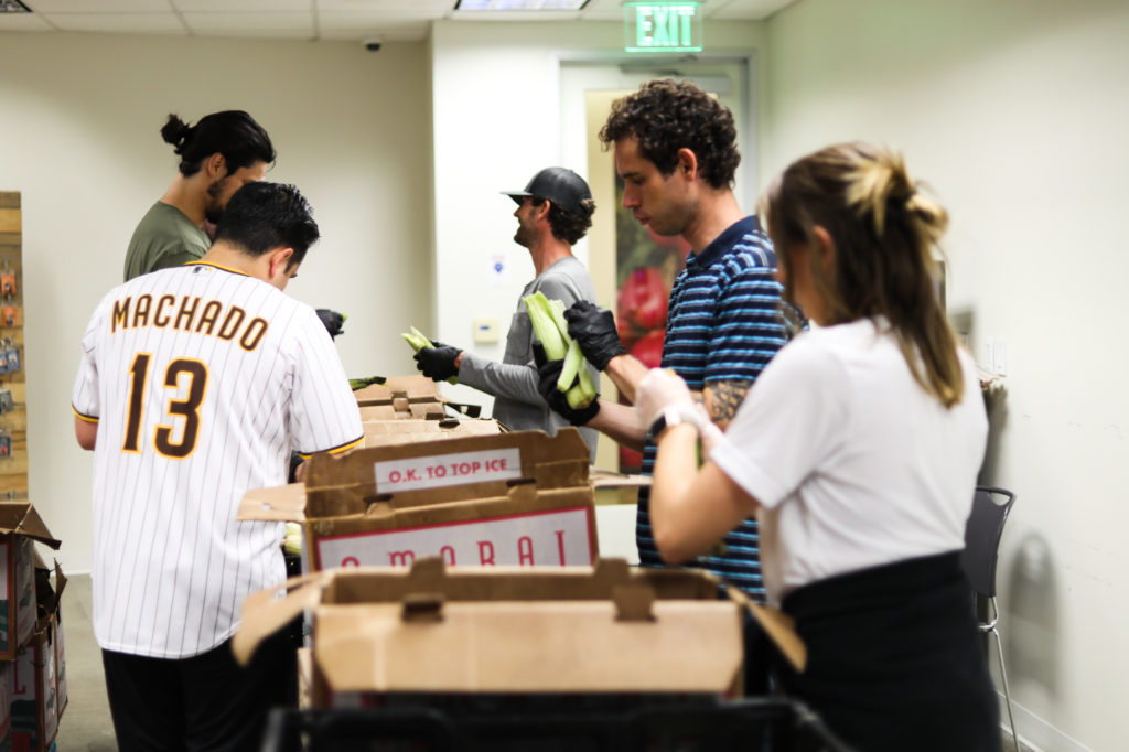 group of men and women shucking corn over cardboard boxes