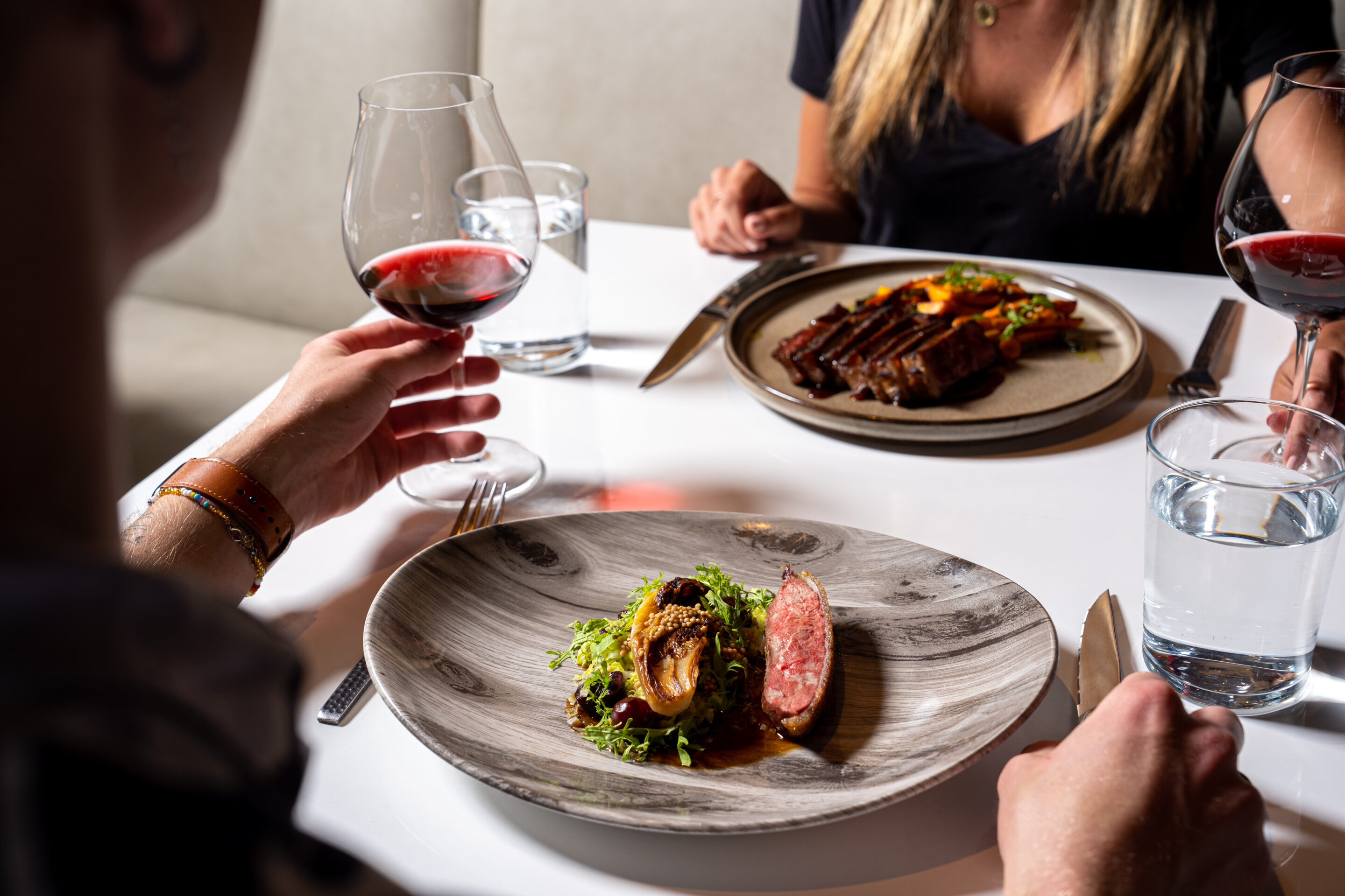 Two dishes with wine glass being raised.