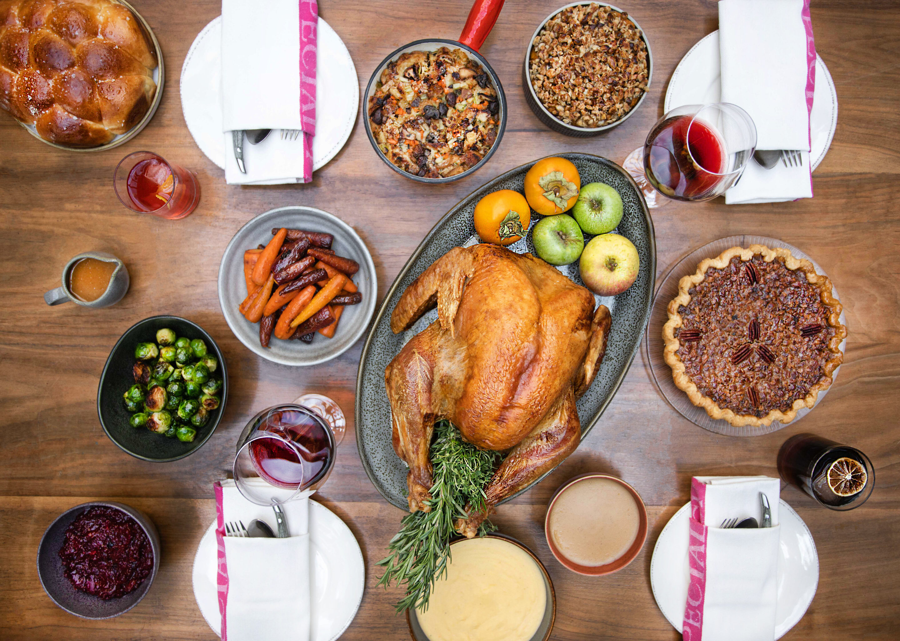 Table of thanksgiving dishes including turkey, pies, vegetables, and plates.